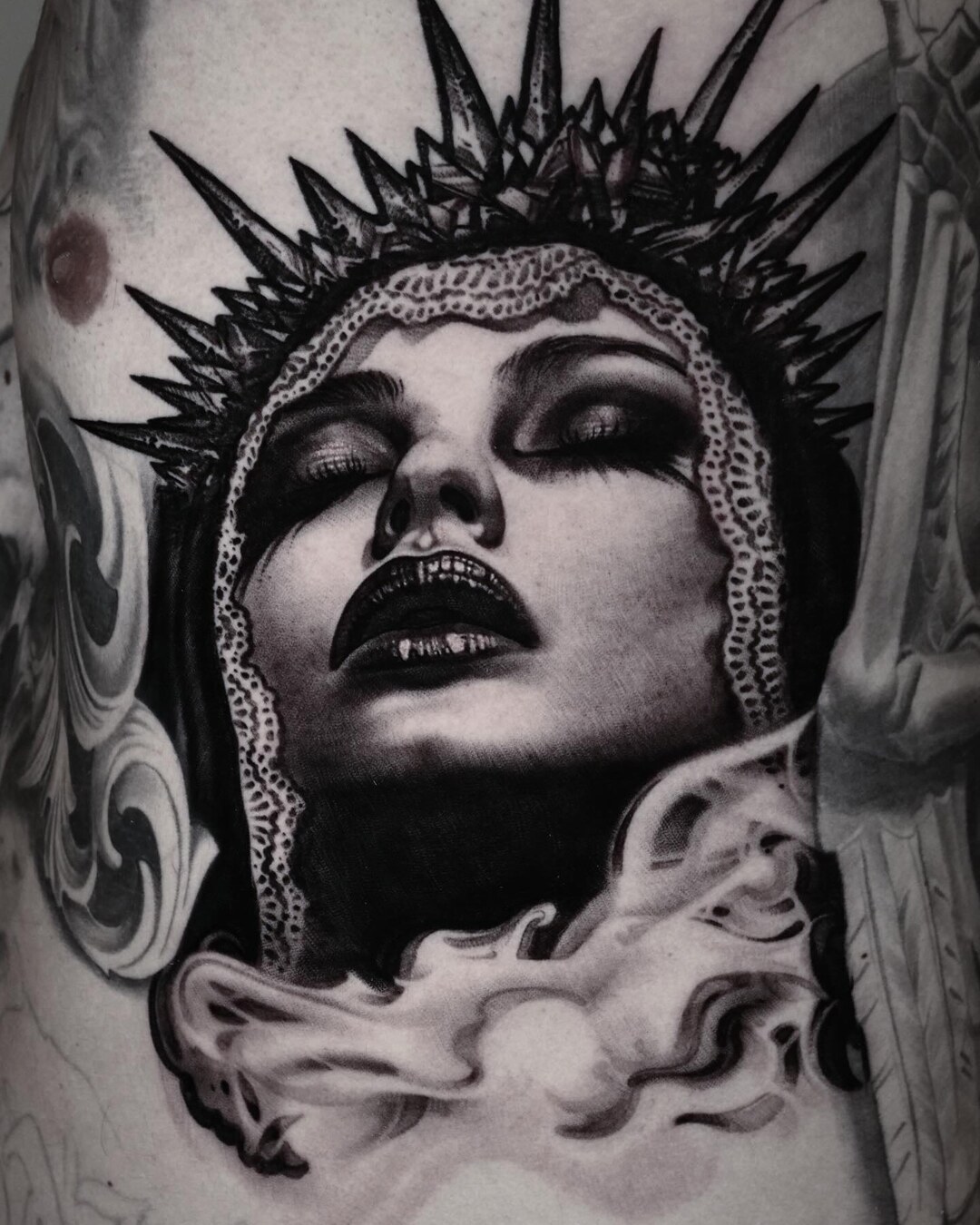 Black-and-grey portrait tattoo of a woman with a spiked halo