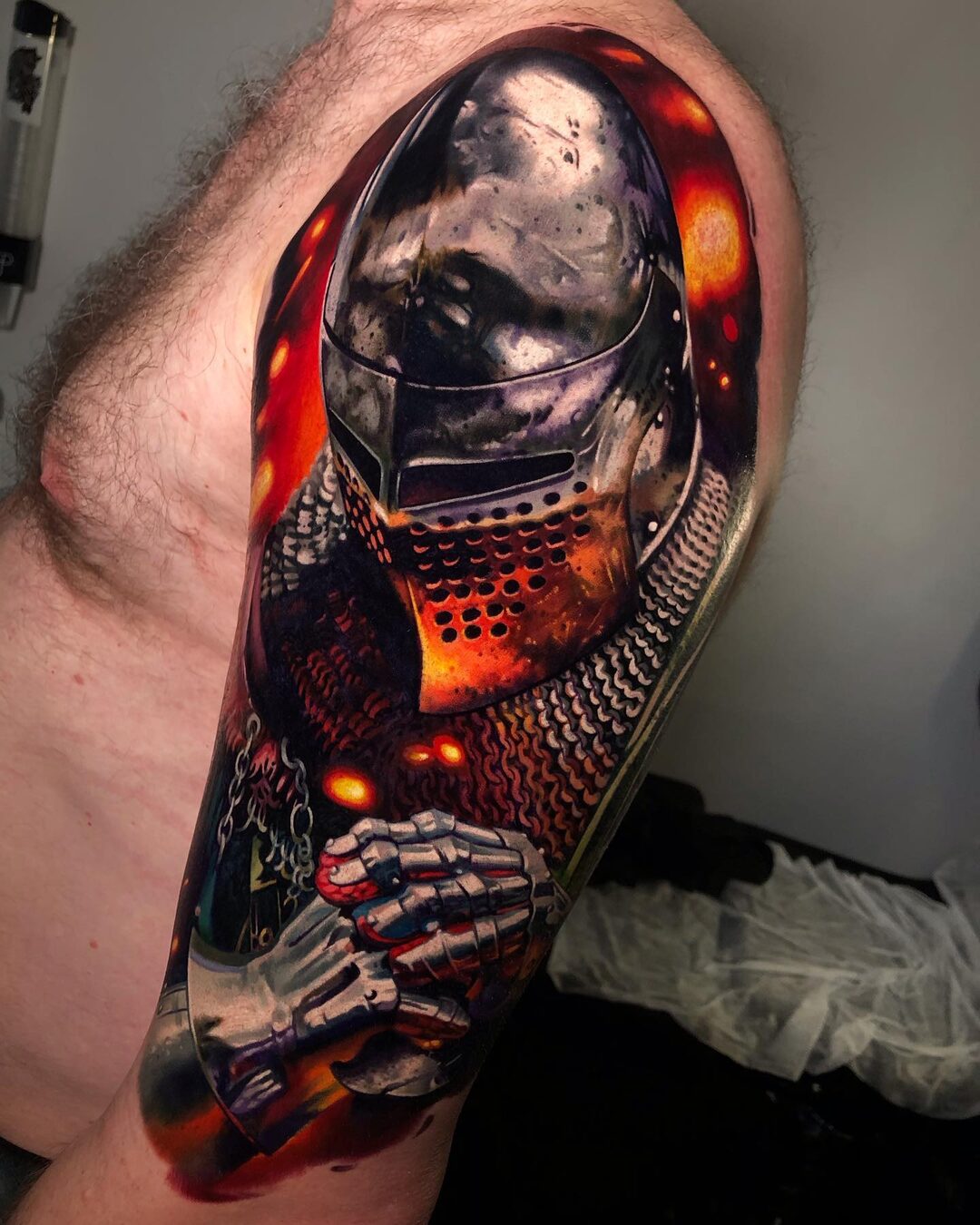 Black-and-grey armored warrior tattoo with warm orange details